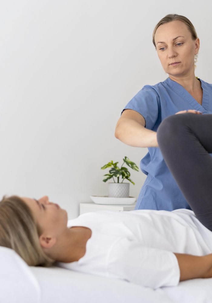physiotherapist-helping-young-female-patient-her-clinic