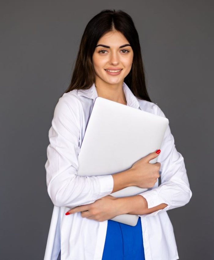 young-woman-holding-laptop-looking-camera-gray-background
